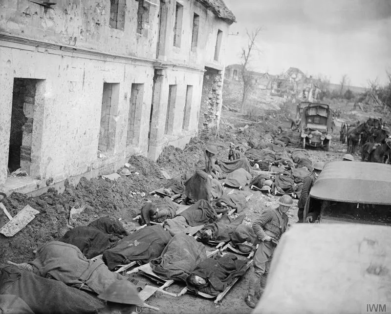 Stretcher cases awaiting transport to a Casualty Clearing Station lie on the ground outside a dressing station at Blangy near Arras, April 1