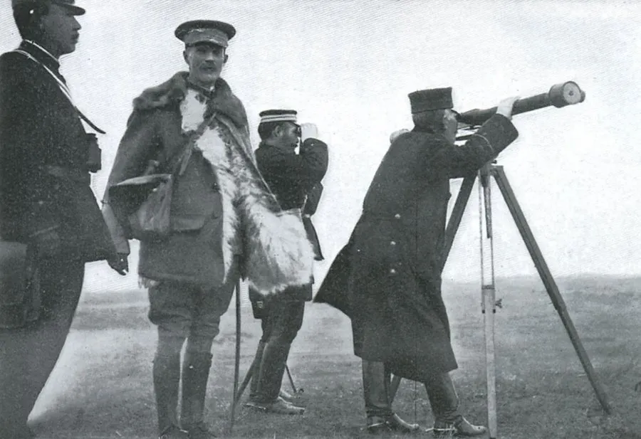 Japanese officers with binoculars and a tripod telescope beside a tall British officer in a fur-lined greatcoat