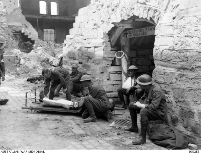 Medical corps men fitting a Thomas hip splint to a wounded soldier outside a regimental aid post near Ypres